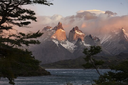 Cuernos del Paine in morning light, granite peaks with clouds and snowfields, Lake Peho&eacute; in the foreground with trees as a natural setting, Torres del Paine National Park, Patagonia, Chile