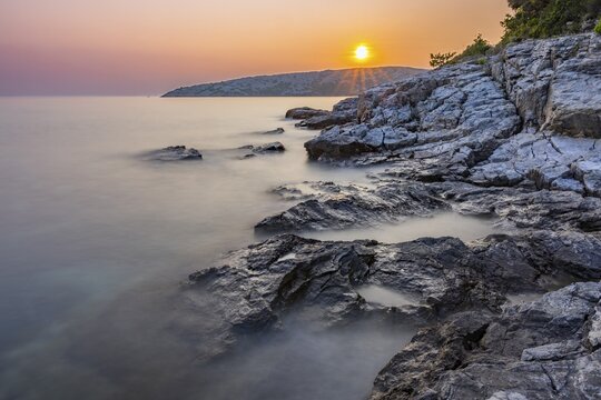 Sunset over crystal clear water on the beach of Ustrine Bay on the island of Cres, long exposure, Croatia