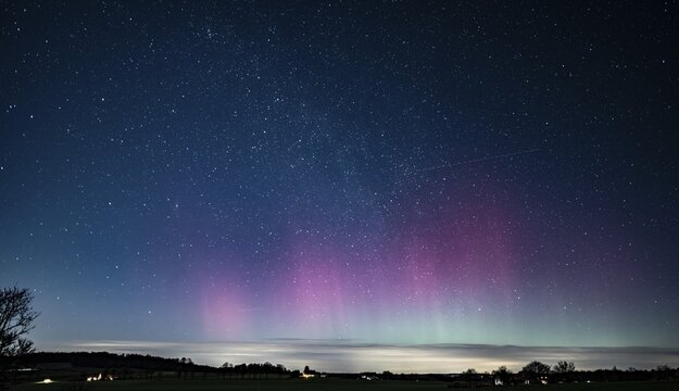Glowing polar lights in shades of purple and green under a clear starry sky, EXPO Observatory Melle, Lower Saxony, Germany
