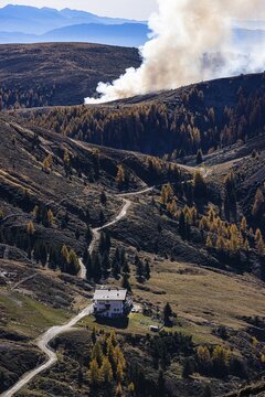 Rising smoke in autumnal landscape, in front the Merano Hut, Merano 2000 ski and hiking area, near Merano, South Tyrol, Italy