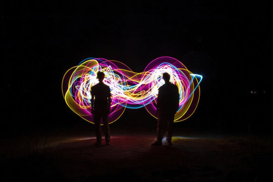 Silhouette di persone con scie di luce colorata a forma di infinito