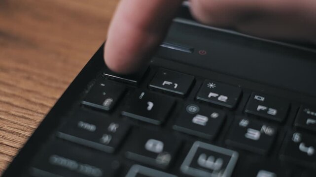 Close-up of a male finger pressing the ESC key on a black laptop keyboard. The gesture signifies cancelling a digital command, exiting a software program, or stopping an operation.