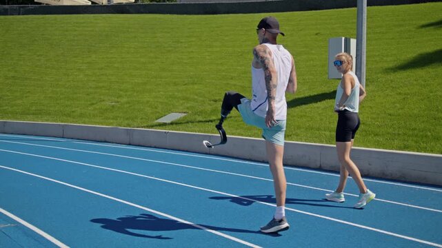 Instructor controls athlete with leg prosthesis raising knees