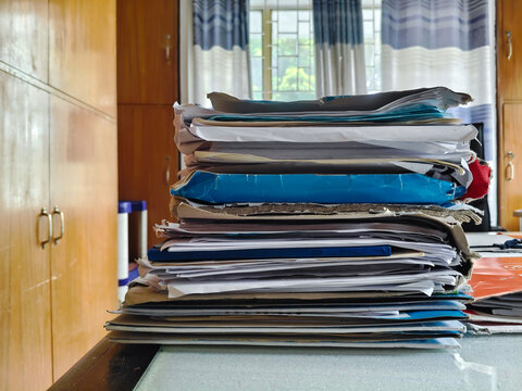 Stack of Papers on Desk with Curtains in Background