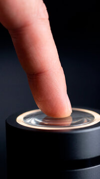Close up finger pressing glowing illuminated power button on sleek black device