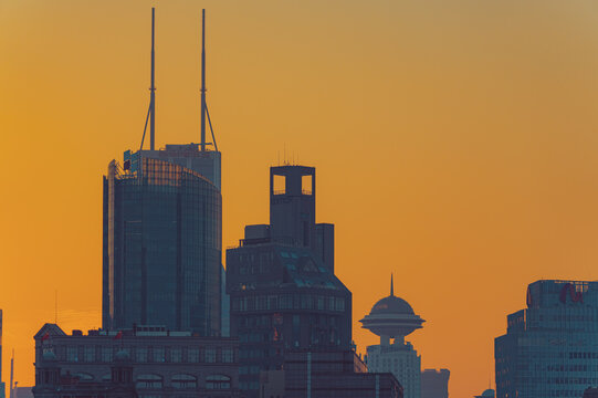View of the Shanghai skyline featuring the Shimao International Plaza and Radisson Blu Hotel silhouettes against a golden sunset sky in Shanghai, Shanghai, China.