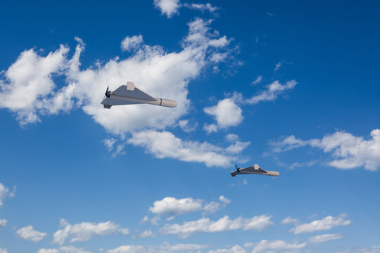 3d render of Shahed style one-way attack drones in front of blue sky with clouds. Selective focus on closest drone