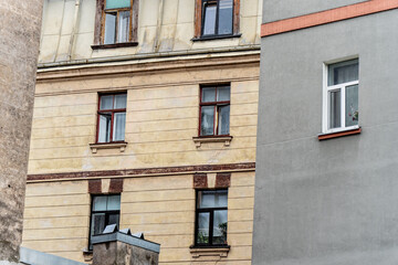 Obraz premium Detailed view of historic yellow concrete building architecture contrasting with a sleek contemporary grey residential wall in the city