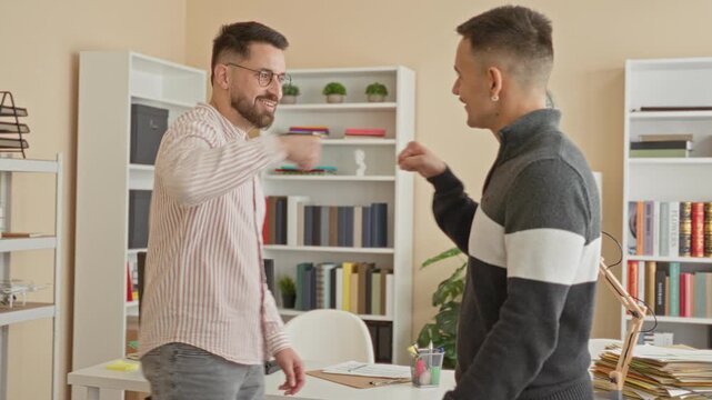 Man extending hand for handshake and occasional fist bump across cluttered desk with papers, lamp and bookshelves in office building; friendly teamwork.