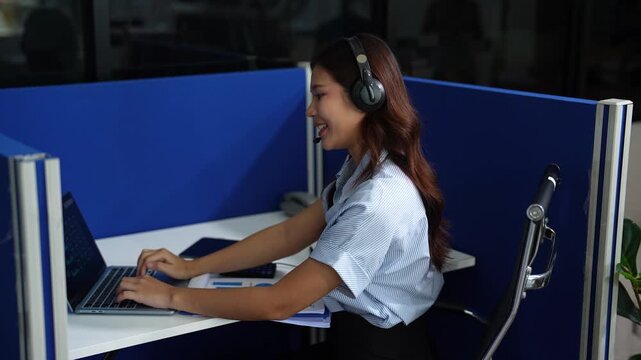 Friendly smiling female call-center agent with headset working on support hotline in office.