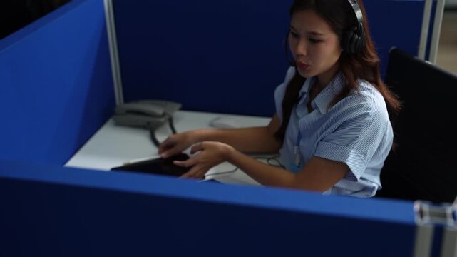 Friendly smiling female call-center agent with headset working on support hotline in office.
