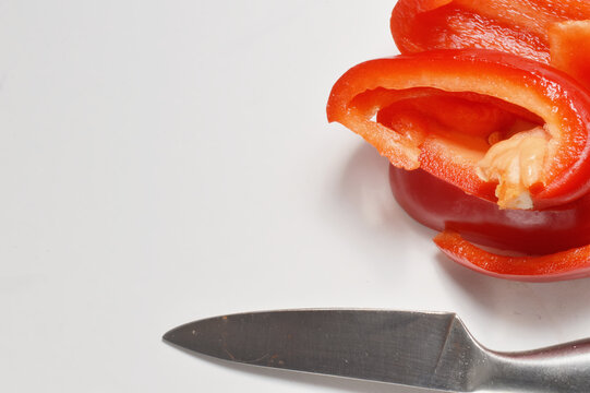 chopped red bell pepper and silver knife against clean white background with generous copy space, red pepper culinary overlay, pepper photo for branding