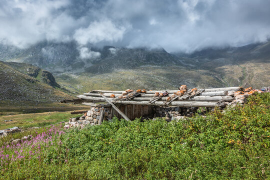 Authentic alpine village with stone huts under a dramatic cloudy sky