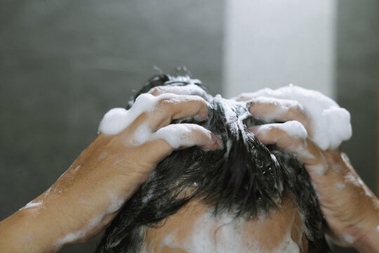 man bathing wash his hair with shampoo in shower. for hygiene. Liquid drops, and foam wash for texture and cleaning routine.	