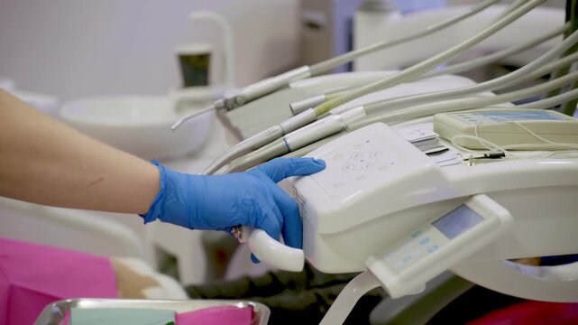 A gloved hand delicately adjusts dental equipment in a contemporary clinic, revealing the precision and craftsmanship of tools used for patient care in slow motion.