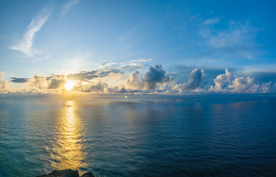 Breathtaking golden sunset over the calm Atlantic ocean with sun rays breaking through clouds at Ponta do Pargo, Madeira, Portugal.