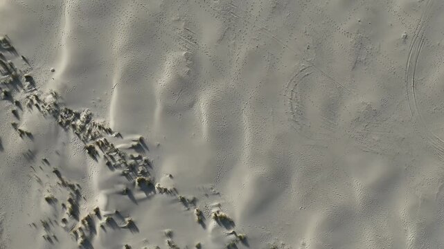 Drone view of footprints wave lines and beach formations.