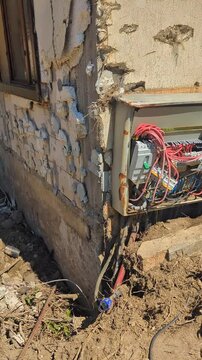 Devastated residential electrical panels caked in mud, debris, and silt after a catastrophic flood