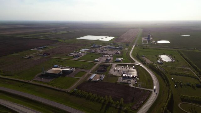 Aerial drone shot of a large hemp oil manufacturing plant in rural Manitoba, showing buildings, processing areas, roads, and summer fields stretching into the distance