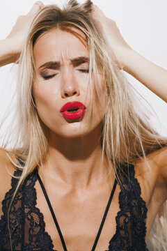 emotions and feelings concept - beautiful blonde lady in sexy lingerie, lost in pure bliss, her radiant skin illuminated by bright studio lighting against a white background