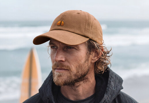 Man at the Ocean Wearing a Cap with Logo Mockup