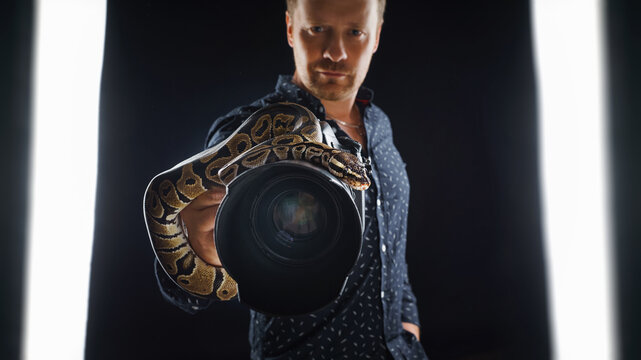A photographer shows a camera with a snake on it. An exotic photoshoot.