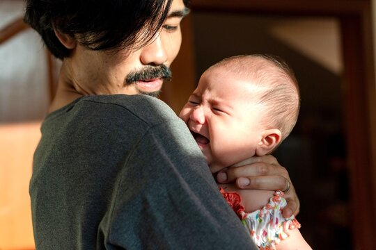 Father comforting crying baby tenderly.