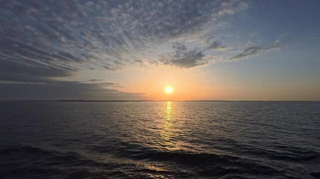 Cinematic morning time-lapse showcasing the dramatic contrast between a bright sunrise and dark sweeping clouds over the ocean.
