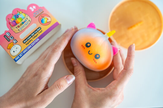 Prague, Czech Republic - June 17, 2026: Person removing Rainbow Mystery Bun squishy toy from surprise container after opening mystery package