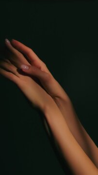 Woman in darkness sensually touching the skin of her arm as she turns