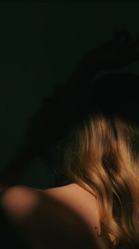 Woman in the dark sensually touching the skin of her arm as she turns around