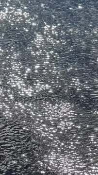 Bright sunlight reflects off the surface of the water. A sparkling, endless expanse of water, ripples and reflections on the river's surface. The river current sparkles, summer