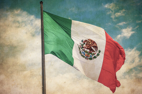 Grunge image of Mexico flag over blue cloudy sky