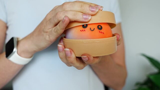Woman opening container with cute unicorn squishy bun toy. Stress relief toy and sensory fidget concept