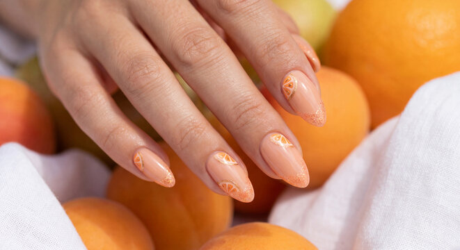 orange citrus nail art manicure with fruit slices and gold glitter french tips design
