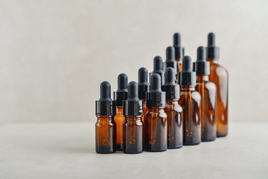 Amber glass dropper bottles of different sizes arranged in ascending order from smallest to largest on light background.