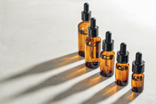 Amber glass dropper bottles of different sizes arranged in ascending order from smallest to largest on light background.