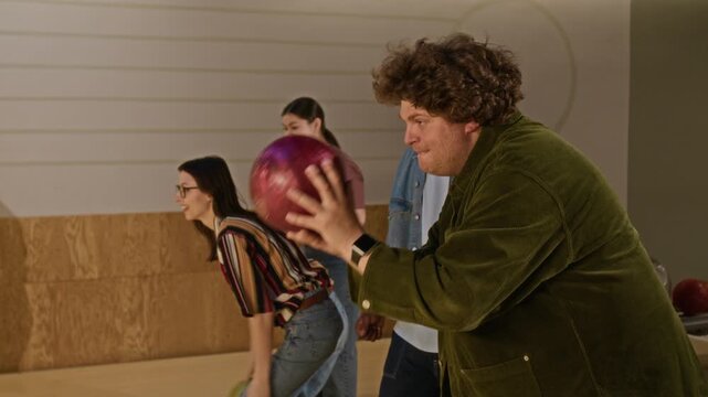 Multiethnic young friends playing bowling and celebrating successful throw while teasing opponents. Ideal for advertisements promoting indoor entertainment, team building, or youth lifestyle brands
