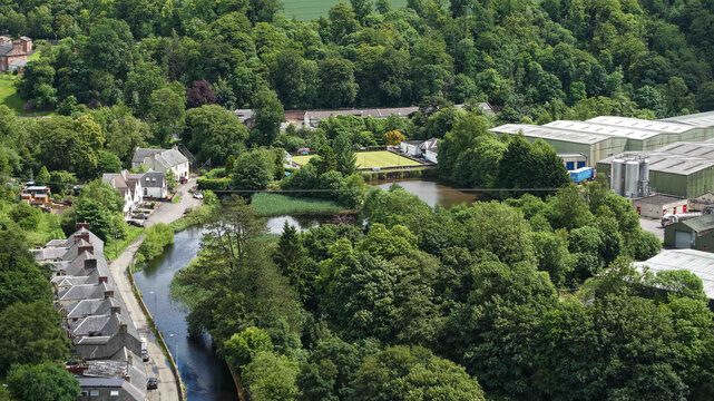Catrine, South Ayrshire. 9th of June 2026 Village river ayr flowing through green forest near industrial buildings.Aerial view showing a village, river ayr, lush trees, and factories
