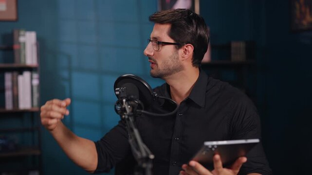 Portrait of man host with digital tablet interviews guest on podcast show in studio. Bearded presenter discusses break news at microphone in office. Wold policy