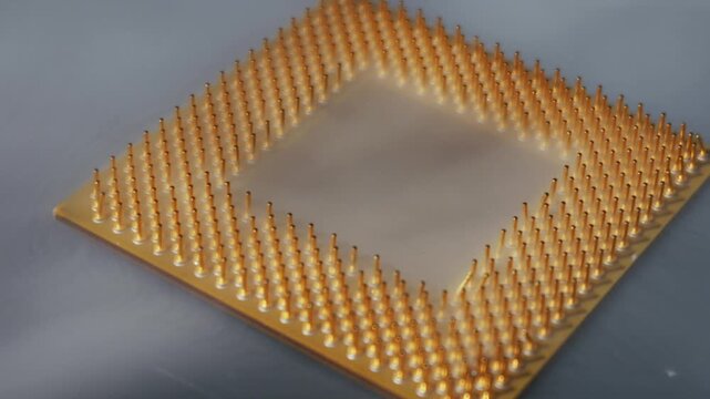 Computer CPU processor with a pin grid array emerges from dissipating cold vapor. Macro shot focuses on the golden pins against a dark, reflective background.