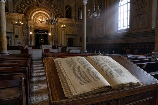 Empty synagogue interior with wooden lectern and ancient scripture, soft window light.