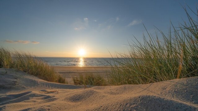 Panoramic landscape background banner panorama of sand dune, beach and ocean North Sea with blue sky, clouds and sunbeams sunset