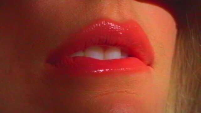 Close-up woman's bright pink lips and perfect white teeth seducing the viewer and biting lip. VHS video noise effect