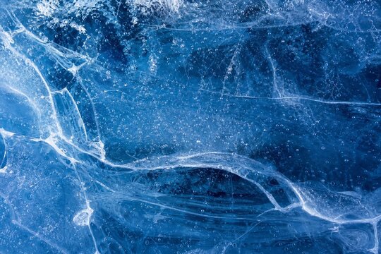 Inside a glacier, blue textures and white veins from frozen bubbles.