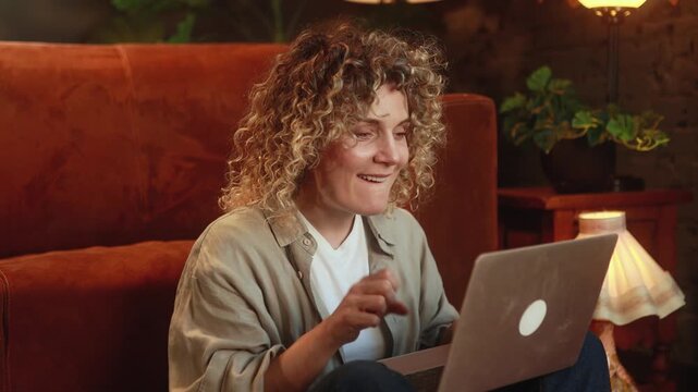 Horizontal video of curly haired woman anxiously waiting for important notification and celebrating success after receiving good news on laptop. High quality 4k footage