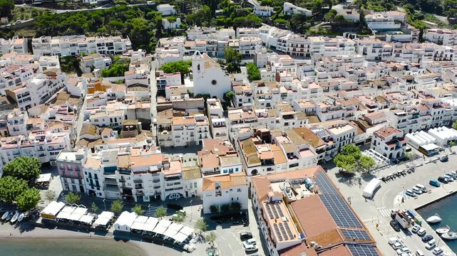 Drone view of Port de la Selva, a charming fishing village on the Costa Brava, featuring its harbour, whitewashed houses and the surrounding Cap de Creus landscape. 