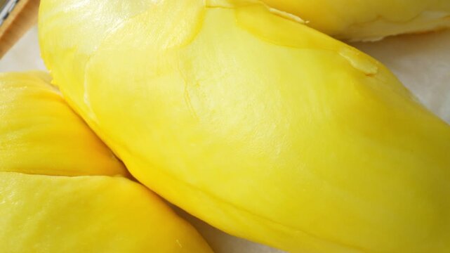 Close-up view of premium durian flesh with smooth surfaces and vibrant yellow color. Perfect for gourmet food presentations, luxury fruit products, and authentic tropical cuisine. 4k.
