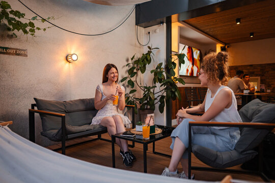 Women friends enjoying conversation and drinks on a cafe patio