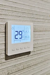 Smart digital thermostat installed on modern textured wall, closeup © Alex Tihonov